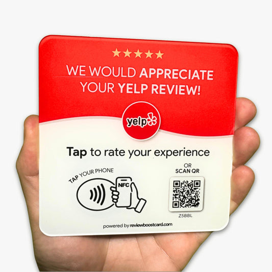 A hand holding a ReviewBoost plaque requesting Yelp reviews, featuring an NFC tap area and QR code for easy review submission