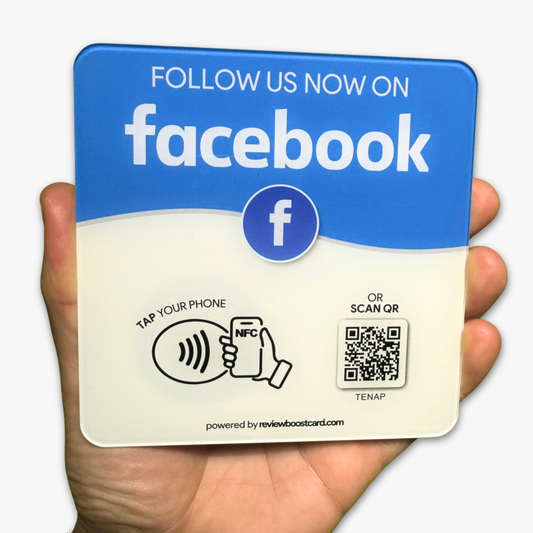 A hand holding a plaque that encourages following on Facebook. The plaque is blue and reads "Follow us now on Facebook. Tap to rate your experience or scan QR." It includes NFC and QR code instructions