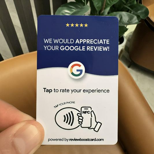 A hand holding a ReviewBoost card, encouraging customers to leave a Google review by tapping their phone or scanning the QR code