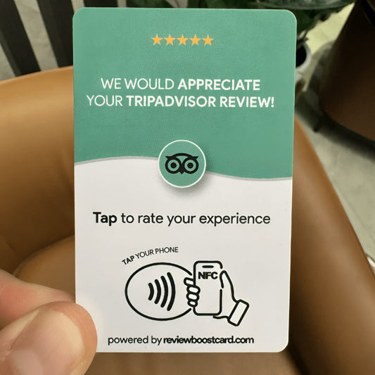A person holding a TripAdvisor review card. The card encourages users to leave a TripAdvisor review by tapping their phone with NFC or scanning a QR code